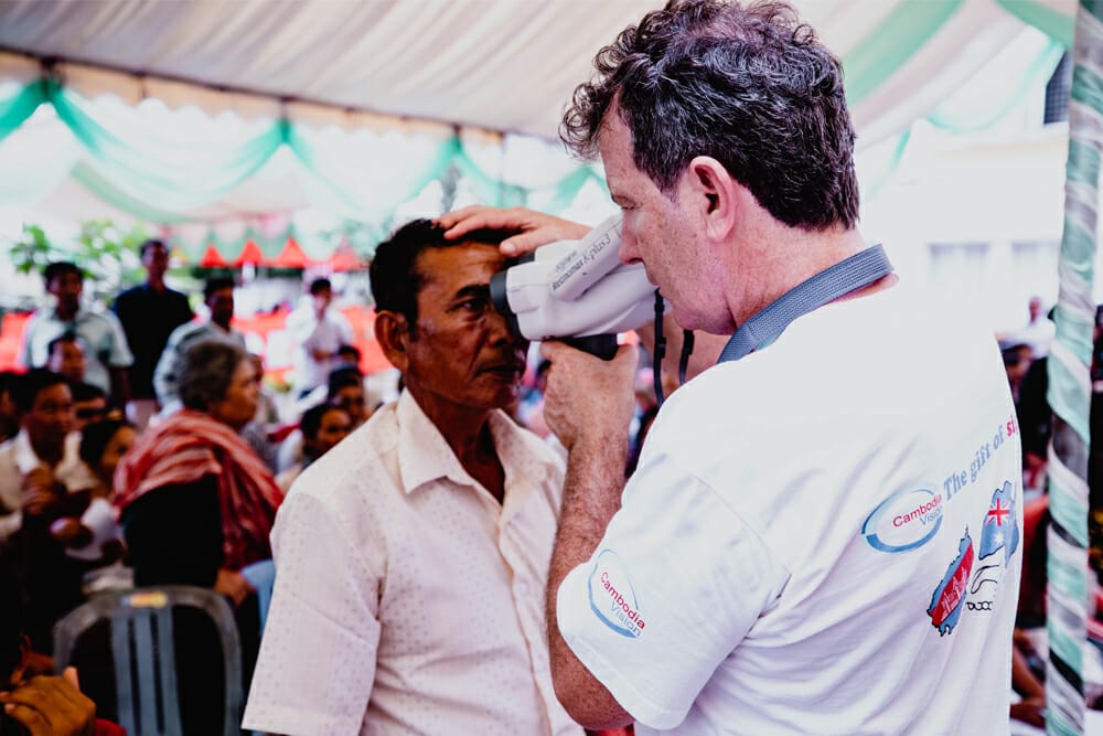 A volunteer examining the eyes of a patient on a previous Cambodia Vision trip.