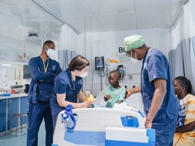 Ella Hawthorne, Ophthalmic Team Manager, and Abram Wodome, Ophthalmic Surgeon, removing Adama, ophthalmic patient, eye patch.