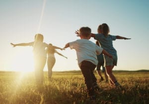 kids run in the park at sunset. friendly family children camp kid dream concept. a group of children run on the grass at the rays fun of the sun silhouette. childhood dream teamwork sunset concept