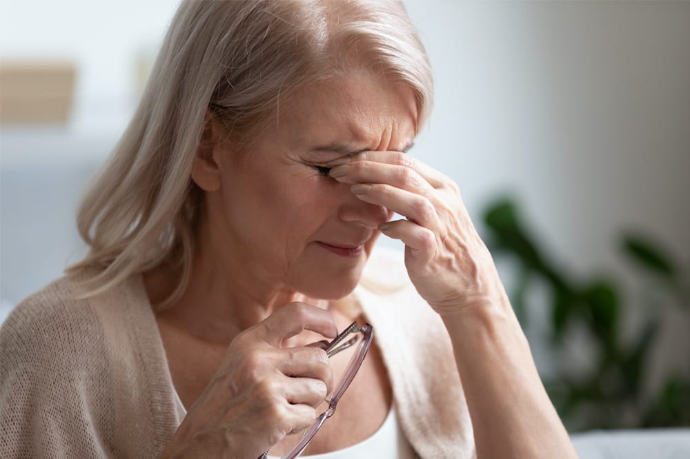 woman with hands to her eyes as if they are sore.
