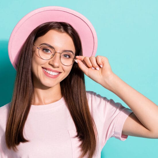 image shows young woman in pink, wearing glasses