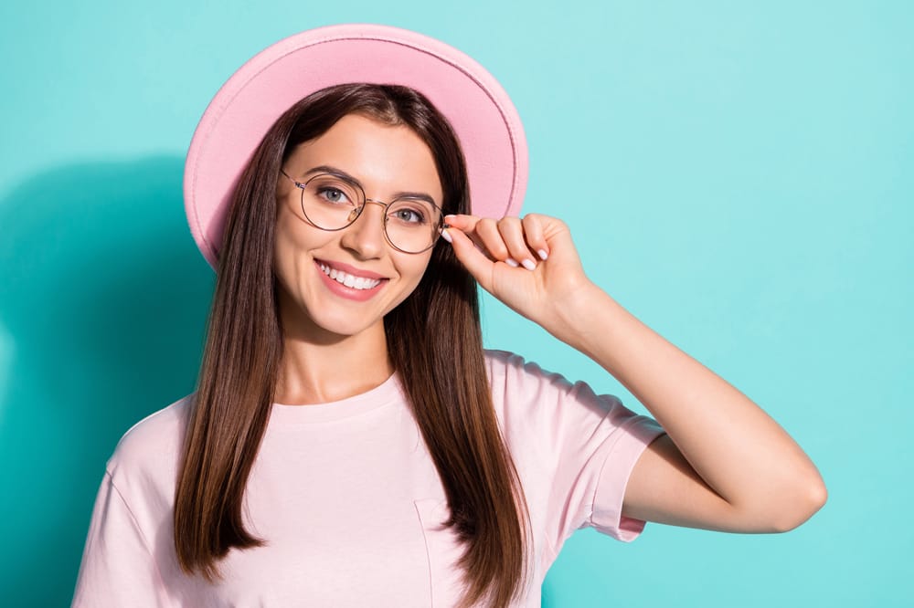 image shows young woman in pink, wearing glasses