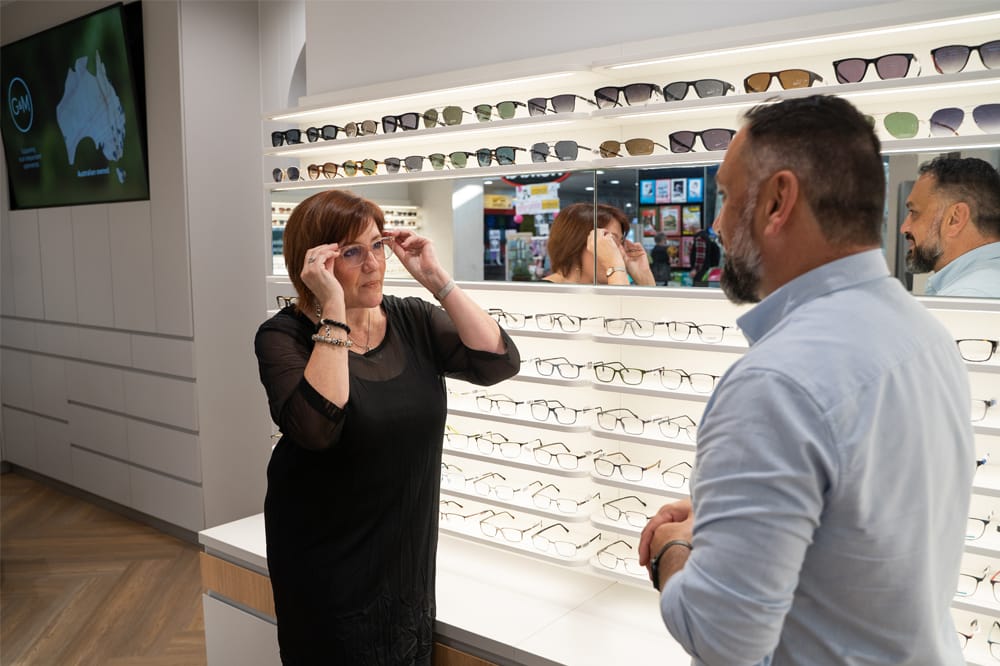 woman trying on frames at a George and Matilda store