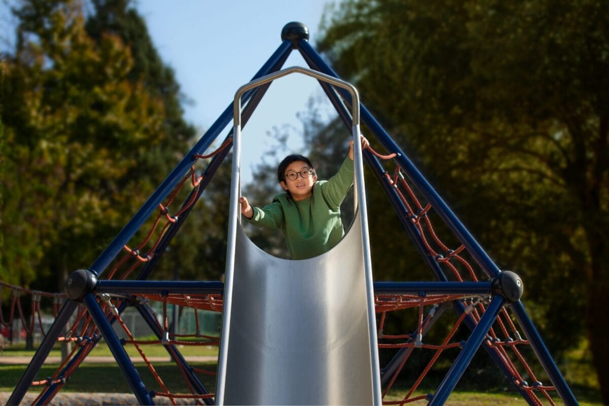 Image shows child on playground equipment, wearing HOYA MiyoSmart lenses