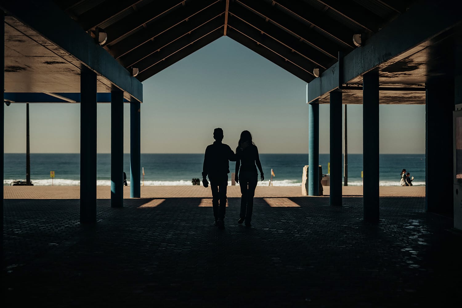 Photo of Em and Mark Cushway at the beach, their backs are to camera, they are watching the water.