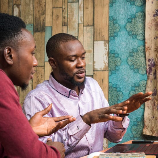 Image shows two men sitting at a comuter discussing results of Eyeonic testing.
