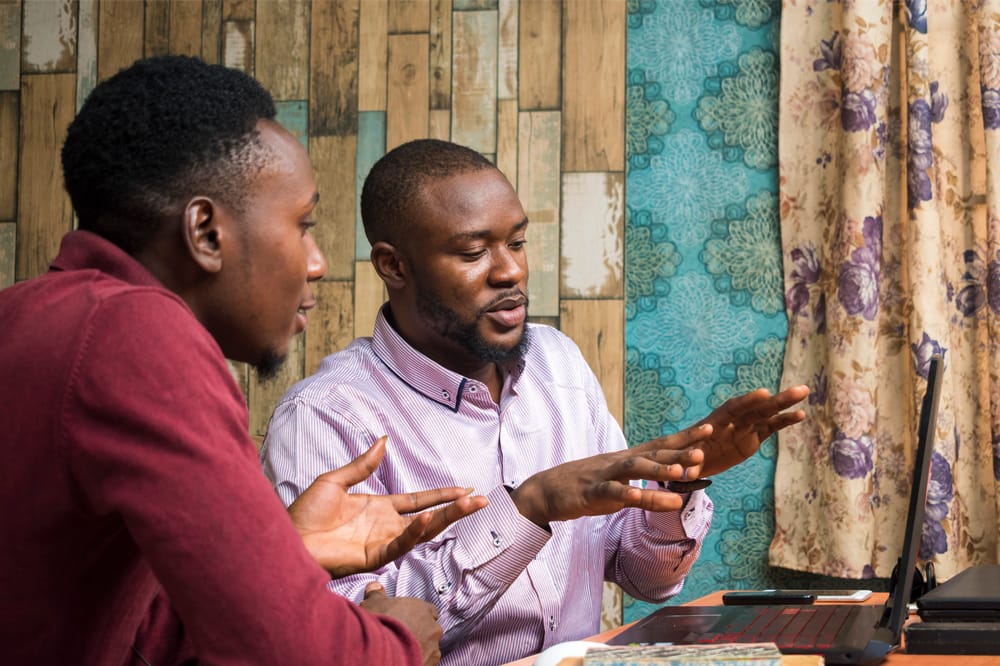 Image shows two men sitting at a comuter discussing results of Eyeonic testing.