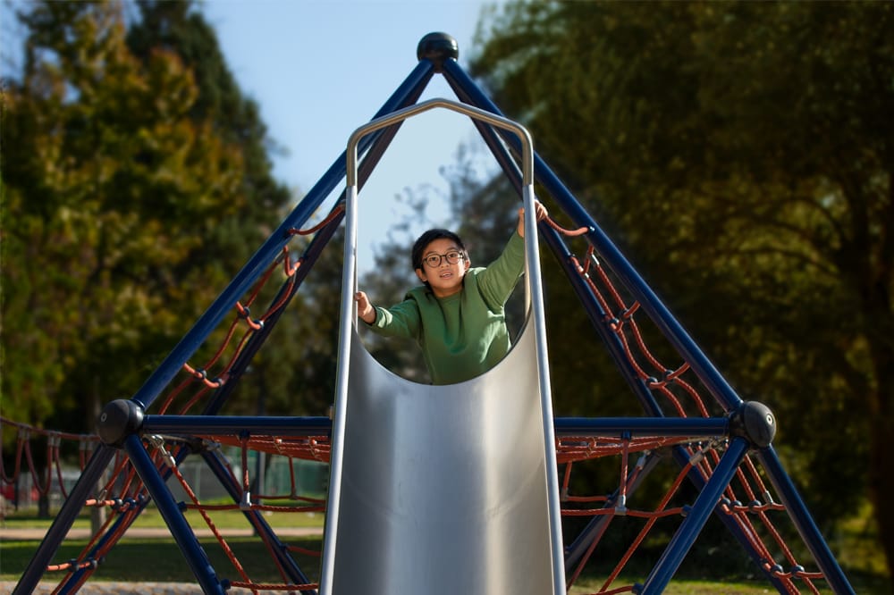 child on slide in playground wearing MiyoSmart
