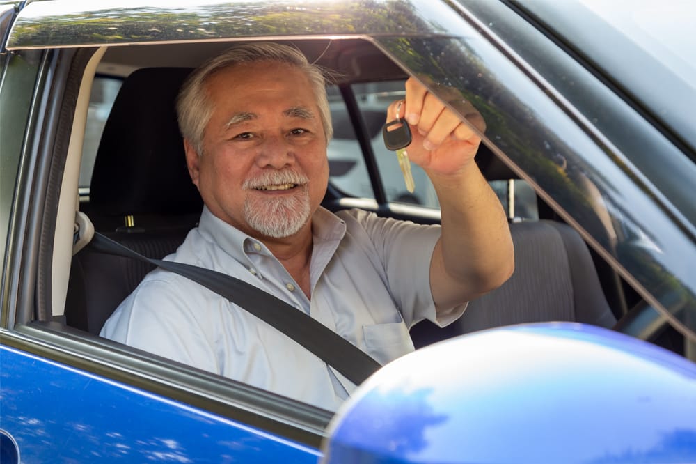 Man in drivers seat holding up keys illustrating fitness to drive.