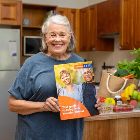 Woman in kitchen holding eye connect brochure