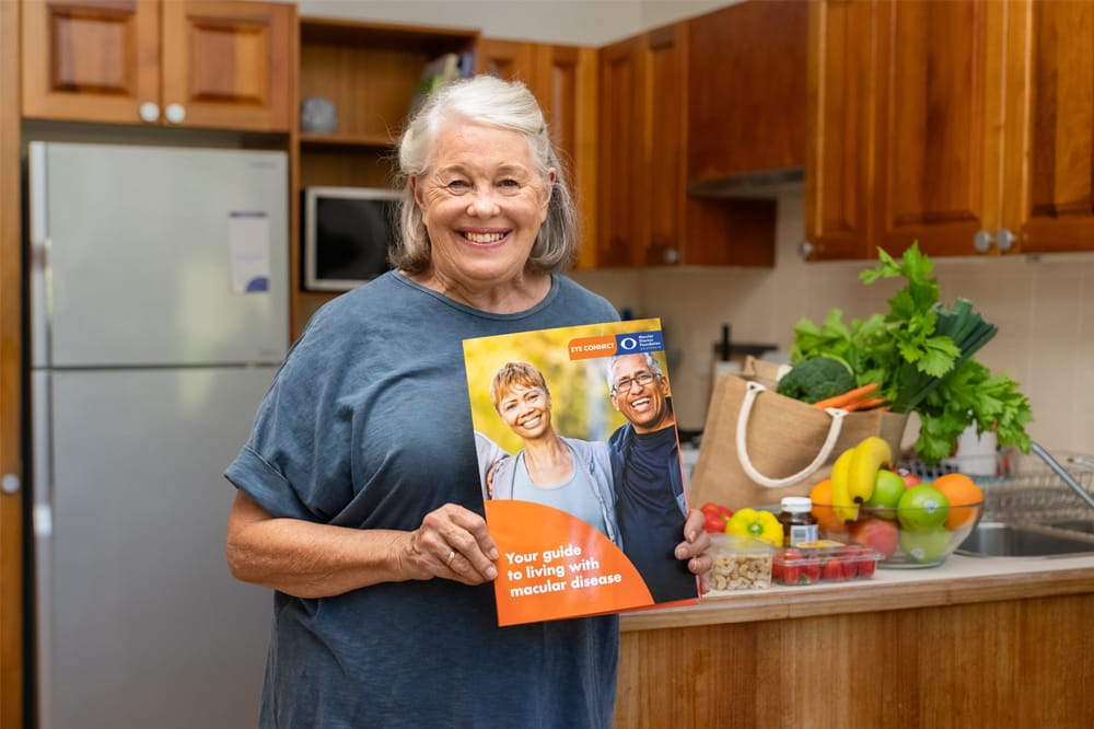 Woman in kitchen holding eye connect brochure