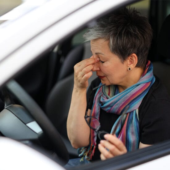 Woman in car, hands to her eyes. Seeway provides practical support to people with ocular conditions.