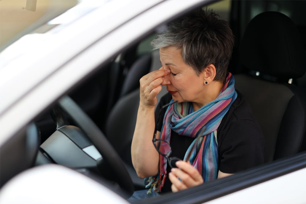 Woman in car, hands to her eyes. Seeway provides practical support to people with ocular conditions.