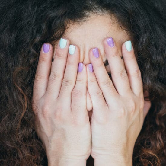woman with autoimmune eye disease, hands covering face