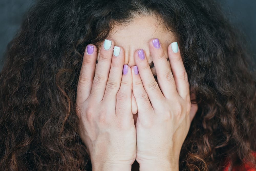 woman with autoimmune eye disease, hands covering face