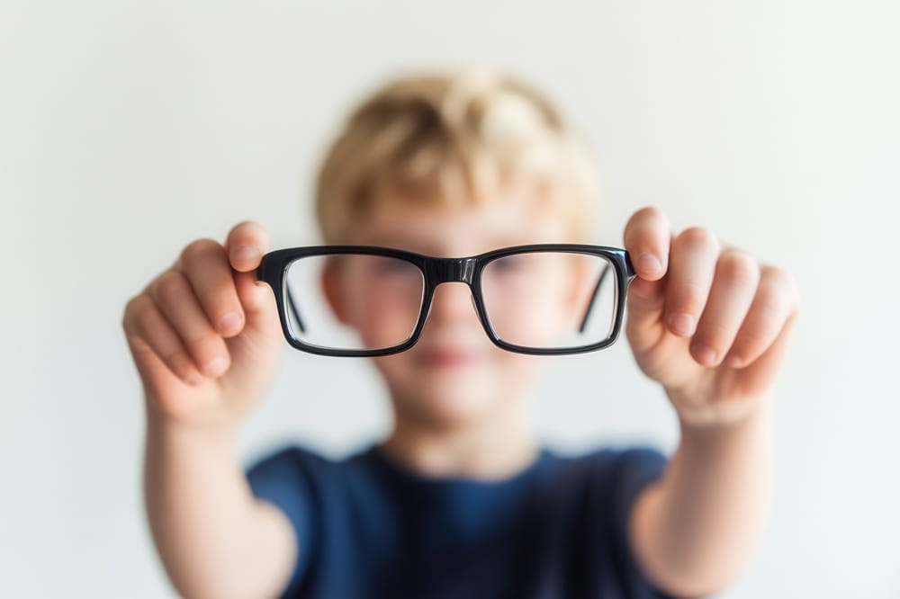 Boy holding glasses. single-vision correction has been the default approach for managing myopia in children. But the evidence is now unequivocal: this strategy is no longer defensible as a first-line treatment.