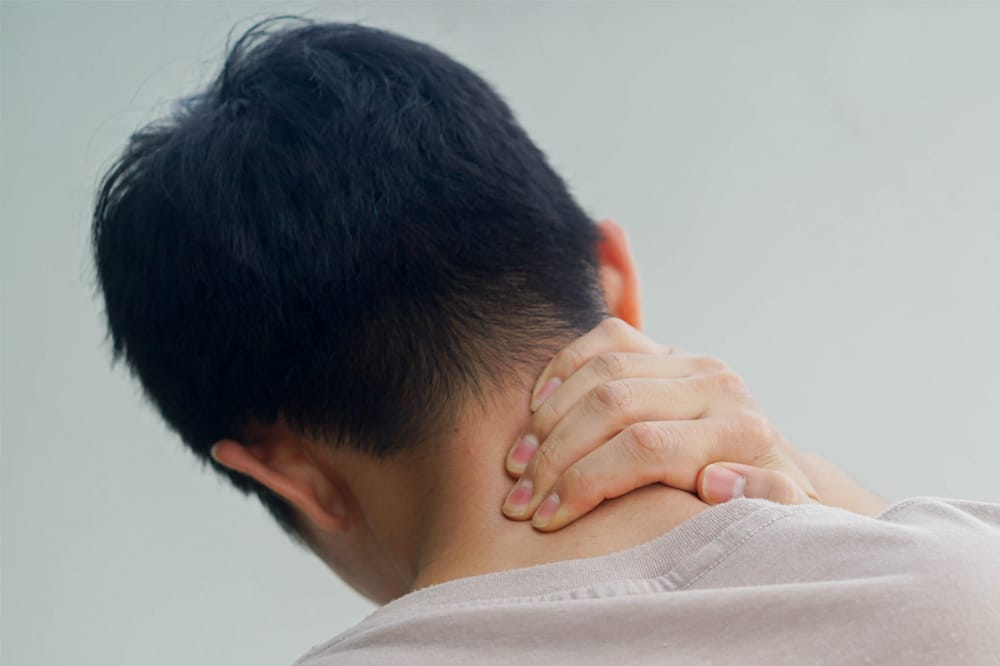Person rubbing neck to relieve a musculoskeletal symptom