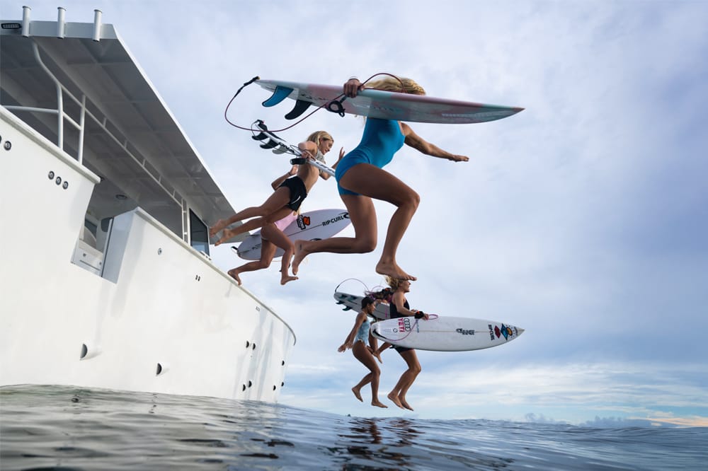 SURFERS jumping into water