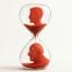 Hour glass with an image of a young man at the top, and an older man at the bottom, representing patient worth of time.